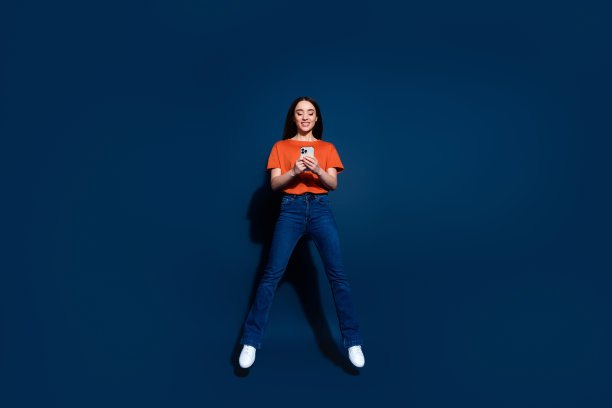 照片正面可爱的好女人穿着橙色的衣服孤立在深蓝色的背景图片下载