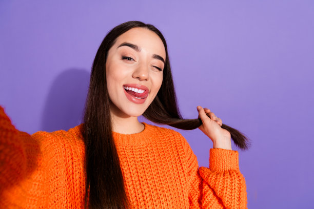 照片中的可爱开朗的女孩穿着时尚的橙色衣服拍摄流孤立的紫色背景图片下载