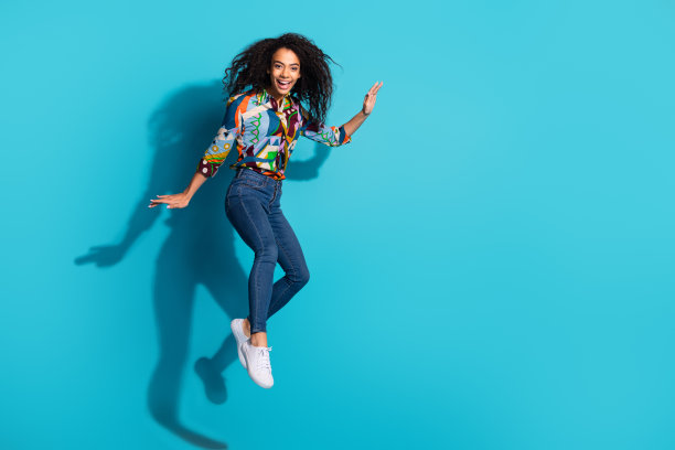 照片中开朗开朗的漂亮女孩穿着时髦的衣服飞空空旷，孤立在蓝色的背景上图片下载