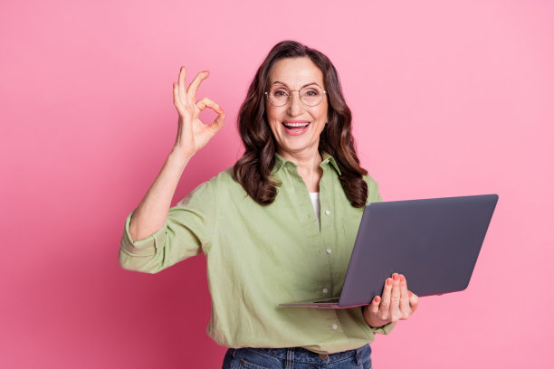 工人高级首席执行官老板公司的照片，穿着卡其色衬衫，使用笔记本电脑，在粉红色的背景上孤立地说“干得好”图片下载