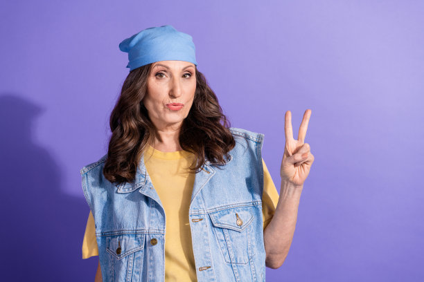 有吸引力的高级妇女的照片肖像显示v字穿着时尚的牛仔裤时髦的衣服孤立的紫色背景图片下载