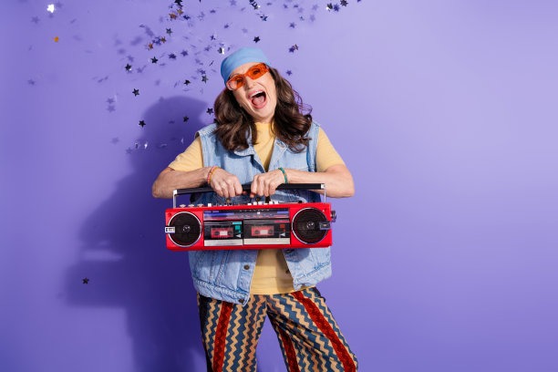 漂亮的退休妇女的照片肖像兴奋地拿着立体声音箱穿时髦的牛仔服装孤立的紫罗兰色背景图片下载
