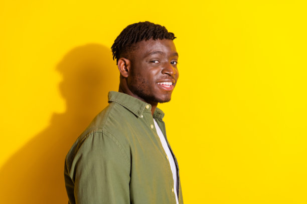照片中时髦酷的家伙穿着卡其色衬衫微笑，空旷的空间孤立的黄色背景图片下载