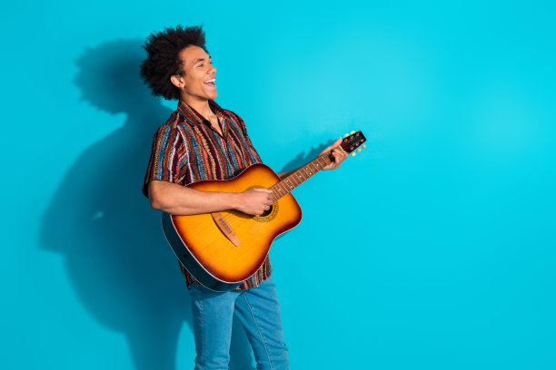 漂亮的年轻人的照片弹吉他唱歌穿衬衫孤立的蓝绿色背景图片下载