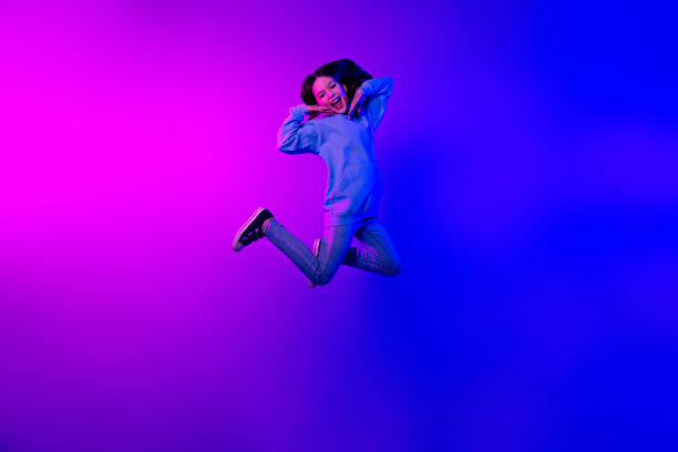 长照片开朗梦幻的小女士穿着连帽衫跳高空空间孤立的霓虹紫色背景图片下载