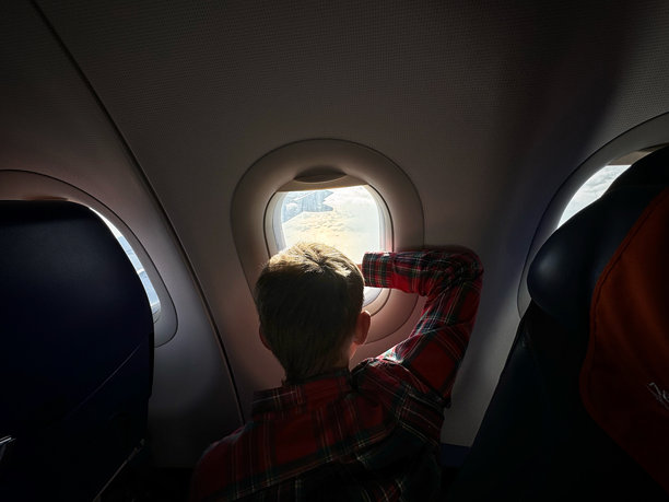 一个白人男孩乘飞机往外看空中的天空图片下载
