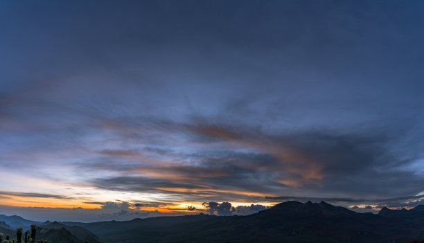 哥伦比亚山区日落全景照片中的强烈色彩，黄色和橙色的云与夜晚的蓝色混合在一起图片下载