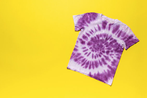 鲜艳的紫色扎染t恤上明亮的黄色背景-时尚潮流股票照片图片下载
