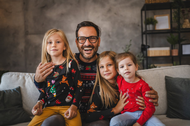 父亲和三个女儿愉快地坐在沙发上的照片图片下载