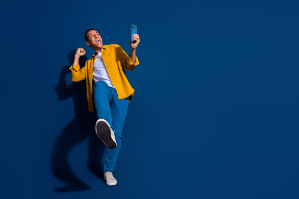 年轻人举起拳头庆祝成就的照片，拿着视频相机手机，视频被隔离在深蓝色的背景下图片下载
