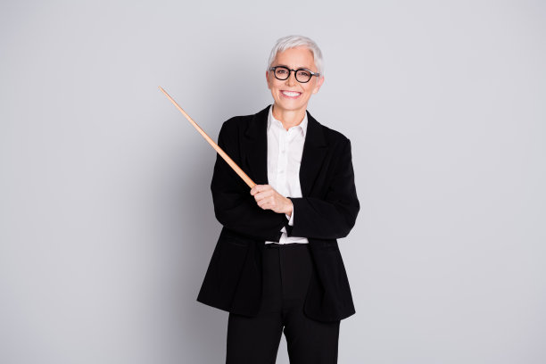 照片漂亮的资深女性专业企业家商学院指针穿正装眼镜孤立在灰色背景图片下载