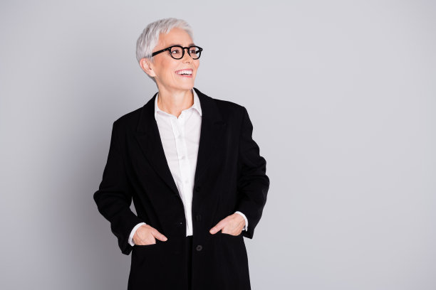 照片中快乐可爱的成功高级女士穿着黑色西装，在灰色背景上显得空空荡荡图片下载