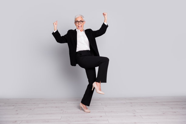 照片中，迷人可爱、喜出望外的高级女士穿着黑色时尚西装，孤立在灰色背景上图片下载