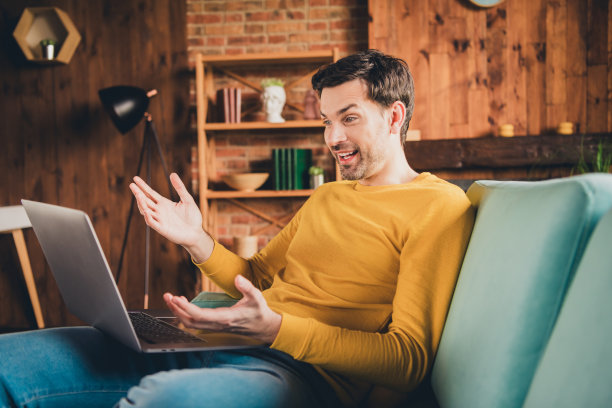 漂亮的年轻人的照片肖像上网本视频通话坐沙发穿黄色的衣服现代室内平坦的室内图片下载