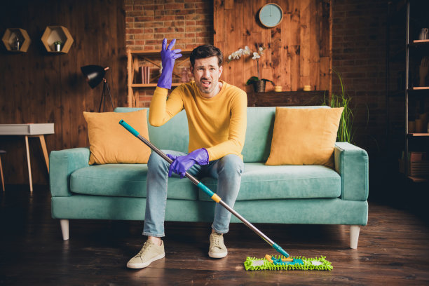 漂亮的年轻人的全身照片拖地清洁房子坐沙发烦恼穿黄色的衣服现代室内平坦的室内图片下载