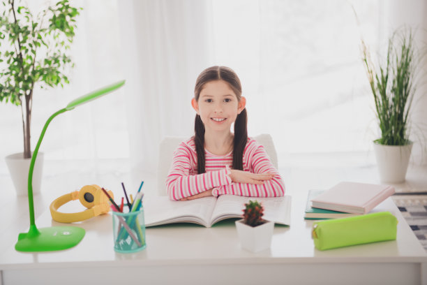 年轻的黑发女学生的照片，微笑着呆在家里准备考试，看书，坐在桌子上度假，孤立在她的房间里图片下载