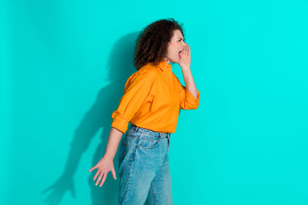 侧面侧面照片的愤怒的女人与波浪的头发穿着橙色的t恤尖叫看起来空旷的空间孤立的绿松石色背景图片下载