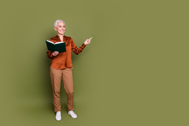 迷人的高级女子的全身照片看书点看空穿着棕色正装孤立在卡其色背景图片下载