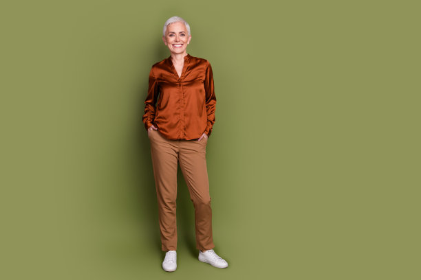 可爱的退休女士的全身照片自信的双手口袋穿着时尚的棕色正装孤立的卡其色背景图片下载