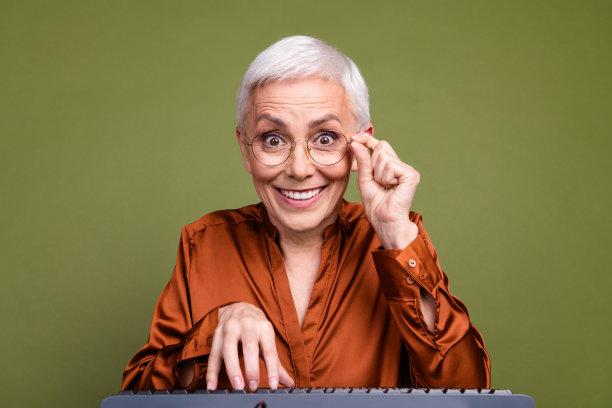 照片肖像漂亮的退休女性打字键盘网络摄像头穿着时髦的棕色正装孤立的卡其色背景图片下载