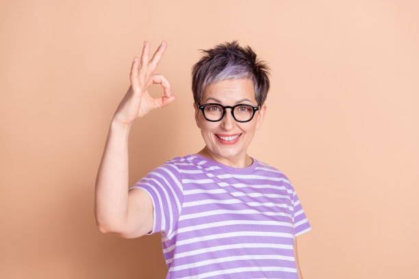 照片中迷人的退休妇女穿着条纹时尚的衣服，标志孤立在米色背景上图片下载