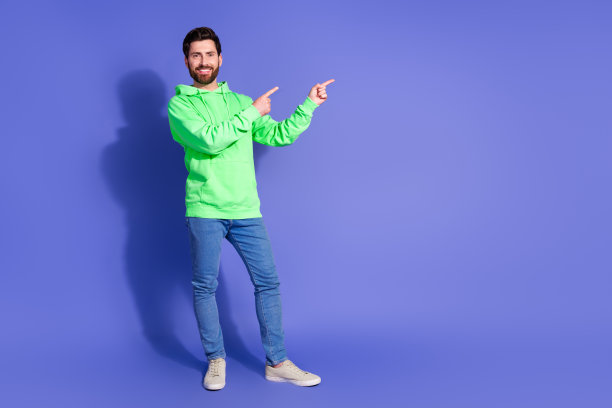 迷人的年轻人的全身照片点空穿着时髦的绿色衣服孤立在紫色的背景图片下载