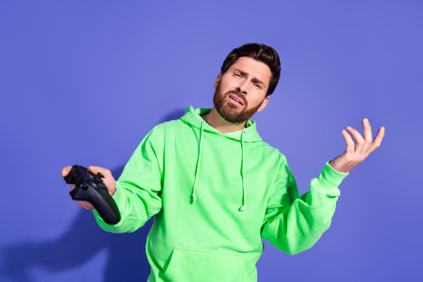 照片肖像英俊的成熟年龄时髦的男人穿着绿色卫衣玩游戏不满失去孤立的紫罗兰色背景图片下载