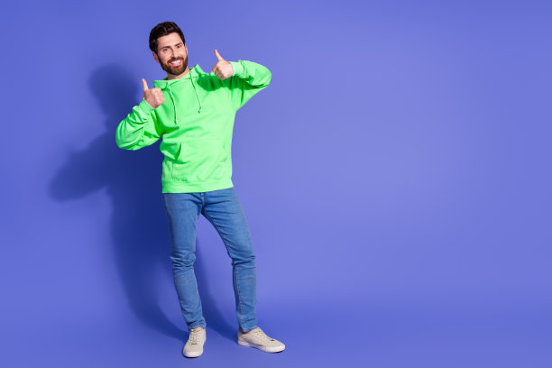 英俊的年轻人的全身照片大拇指赞同穿着时尚的绿色服装孤立的紫色背景图片下载