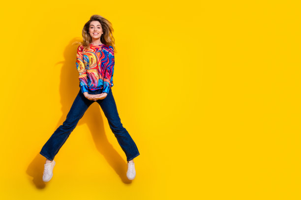 照片的年轻有趣的金发女子穿着彩色套头衫和牛仔裤黑色星期五促销模型孤立的黄色背景图片下载