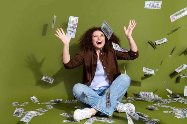 漂亮的年轻女孩的全身肖像，坐在地板上，在卡其色背景上飞钱图片下载