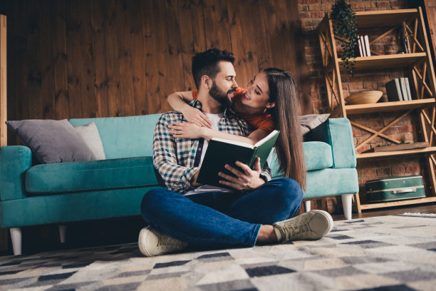 欢快可爱的年轻夫妇的全身照片读书拥抱享受周末玩得开心买新公寓在室内在家里图片下载