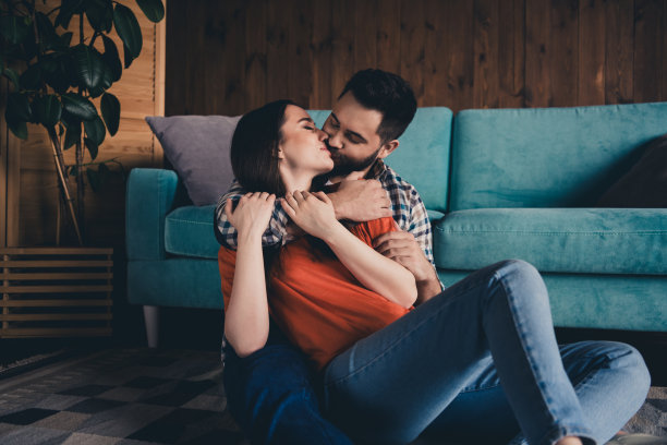 迷人的照片时髦的快乐坐在地板上拥抱亲吻已婚的年轻夫妇花空闲时间搬新公寓的家室内室内图片下载