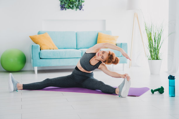 照片中，积极主动的女性穿着运动服在家里的客厅里进行体育锻炼图片下载