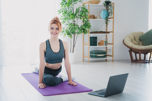 照片中开朗活泼的迷人女子穿着运动服在家里室内看视频做体育锻炼图片下载