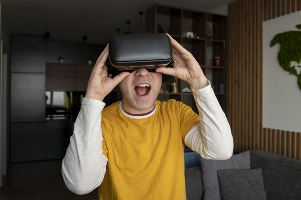 人与技术的概念。年轻的白人男子在家里使用虚拟现实眼镜图片下载