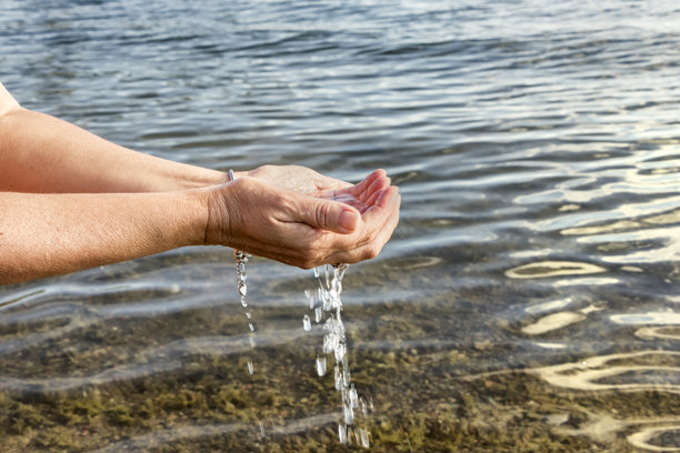 人的手从湖里取淡水。图片下载