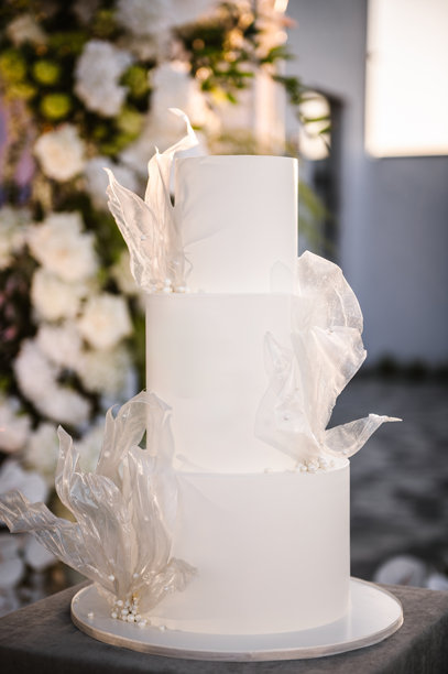 婚礼蛋糕的背景照片区。派对上美味的招待会。夕阳下的时尚蛋糕。婚礼在拱门下举行，在后院宴会厅用鲜花和绿色装饰。图片下载