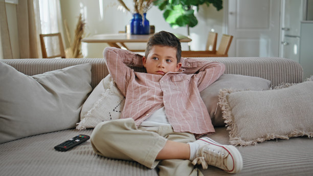 小男孩坐在客厅的沙发上看卡通电视。孩子休息图片下载