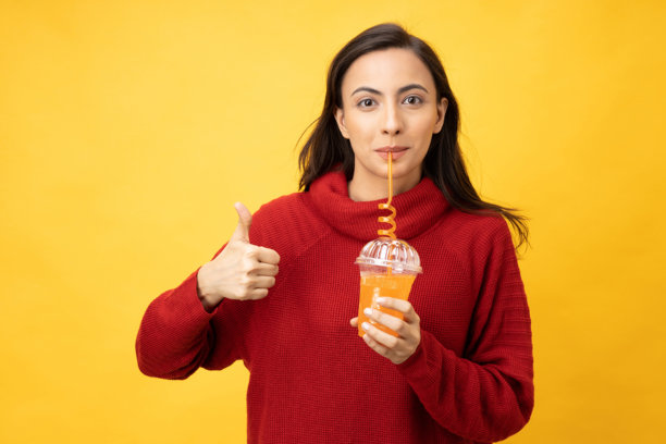 年轻女子的肖像喝冷饮穿针织套头衫孤立的黄色背景股票照片图片下载