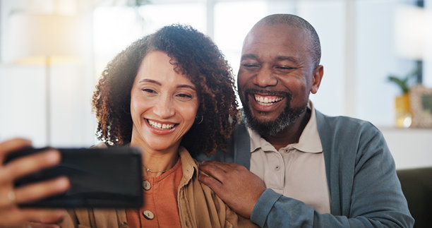 成熟的夫妇，在家里的沙发上自拍和快乐，拥抱，结合和爱在休息室拍照。男人、女人和微笑在沙发上的个人资料照片，回忆或张贴在社交网络上的公寓图片下载