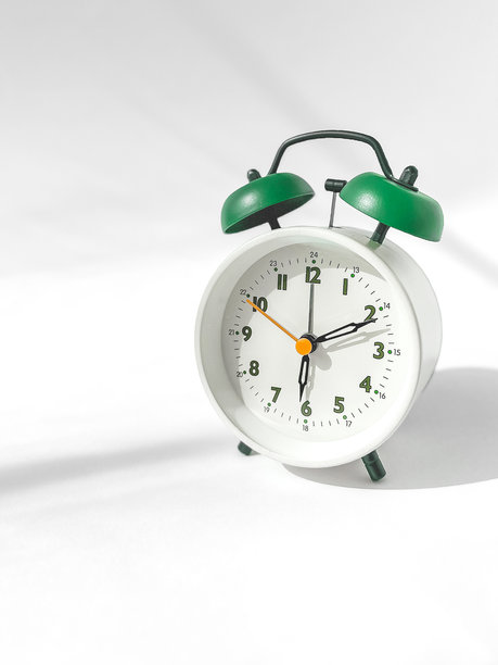 白色背景的亮绿色圆形闹钟的垂直照片，copyspace图片下载