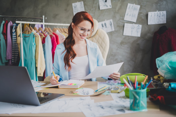 积极的女孩个体户店主的照片坐在桌子上写抄写本在办公室读纸图片下载