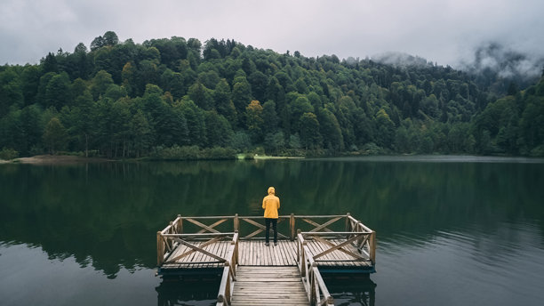 卡拉戈尔自然公园。一个穿着黄色外套、戴着黄色帽子的男人正在欣赏美丽的自然湖景。广角卡拉戈尔照片。土耳其的阿尔温特。图片下载