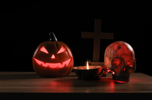 万圣节南瓜与蜡烛，烟，和一个人的头骨在黑色的背景。可怕的万圣节标志图片下载