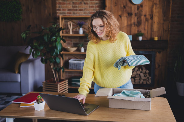 可爱的年轻女性照片包装网上订购衣服上网本穿黄色毛衣舒适现代阁楼办公室室内室内工作空间图片下载