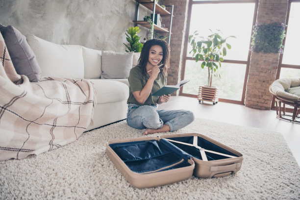 照片积极的好心情的女人穿着绿色的t恤包装衣服暑假写清单在室内房子公寓房间图片下载