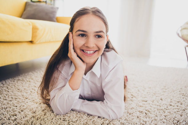 十几岁可爱的女儿的全尺寸照片躺在地板上梦幻放松穿制服远程教育家庭教育孤立的室内背景图片下载
