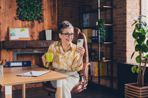 漂亮的高级女性喝咖啡拿着装置穿正装一起工作成功漂亮的光办公室的照片图片下载