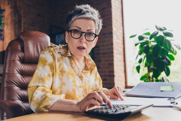 忧心忡忡的退休女簿记员在室内工作站工作区清点报告的照片图片下载