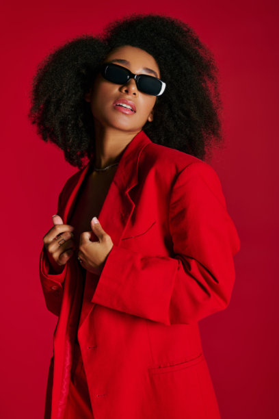 活力四射的年轻女子穿着时尚的红色套装，在大胆的背景下摆出自信的姿势图片下载